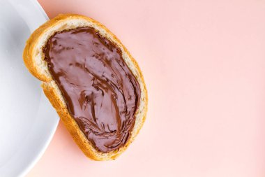 Çikolatalı hamur ve bir plaka üzerinde pembe bir arka plan ile somun parçası. Fındık yapıştırın bir kahvaltı ile sandviç. Üstten görünüm. Kopya alanı 