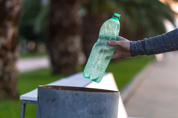 A man throws a plastic bottle in the trash. Waste separation