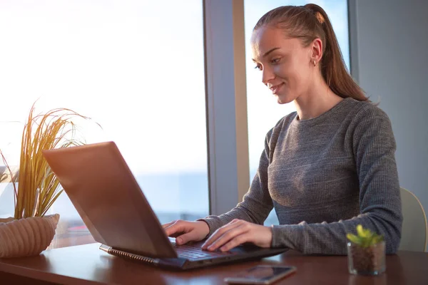 オンラインでの作業と キーボードで入力するためのラップトップを使用して職場で座っている美しい若いビジネス女性 — ストック写真