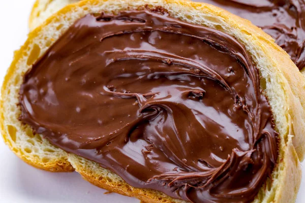 Piece of loaf with chocolate paste spread close up. Sandwich with nut paste on a breakfast