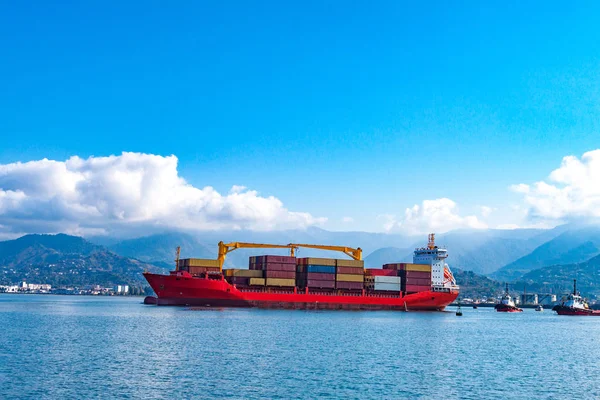 Cargo ship with containers in the sea on a background of mountains. Logistics, transportation of cargo, cargo shipping, goods by sea.