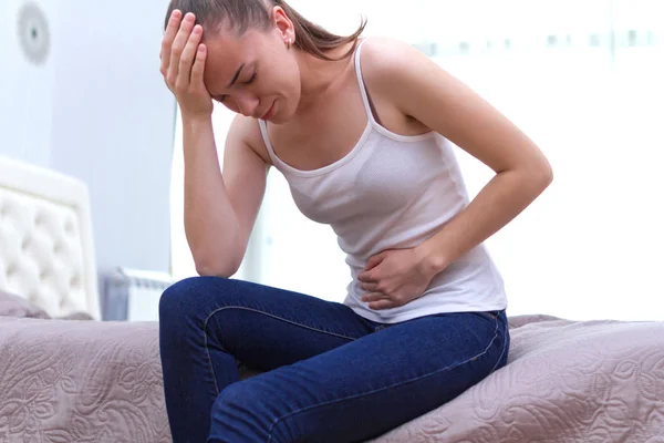 Young woman feels bad and experiences abdominal pain during the period of PMS and menstruation. Painful menstruation. Inflammation and Bladder Infection