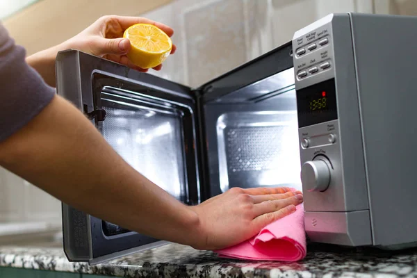 Housewife cleaning microwave oven using lemon and rag