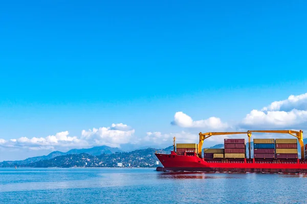Cargo ship with containers in the sea on a background of mountains. Logistics, transportation of cargo, cargo shipping, goods by sea.