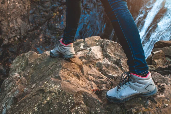 Hiking boots tourist traveler on the background of a waterfall in the mountains. Hiking and climbing. Leisure and travel.