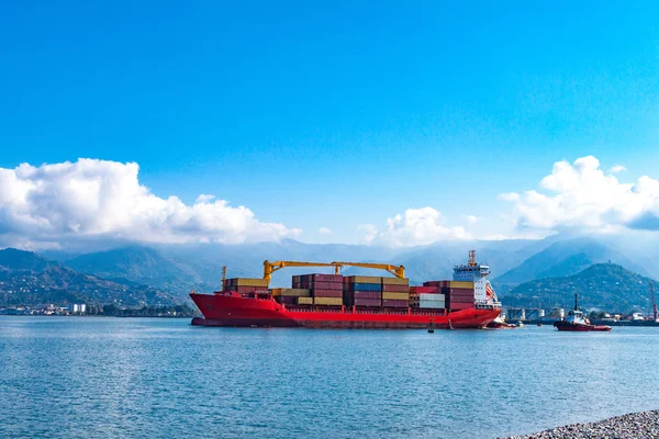 Cargo ship with containers in the sea on a background of mountains. Logistics, transportation of cargo, cargo shipping, goods by sea.