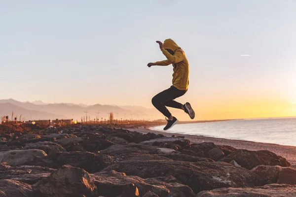 Young Sports Man Hood Making Jump Rocks Sea Mountains Background — Stock Photo, Image