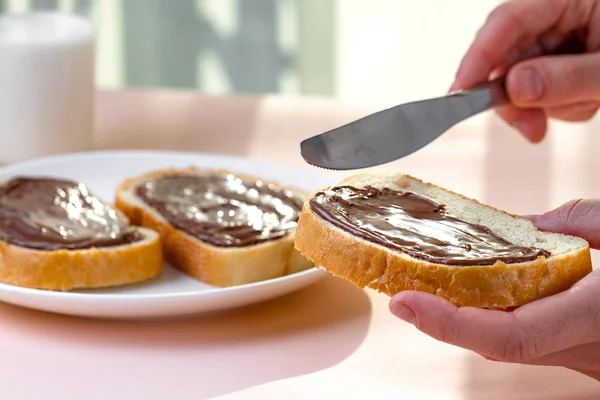 Spread chocolate paste on freshly baked bread. Chocoalte sandwiches with nut, sweet paste for a breakfast.