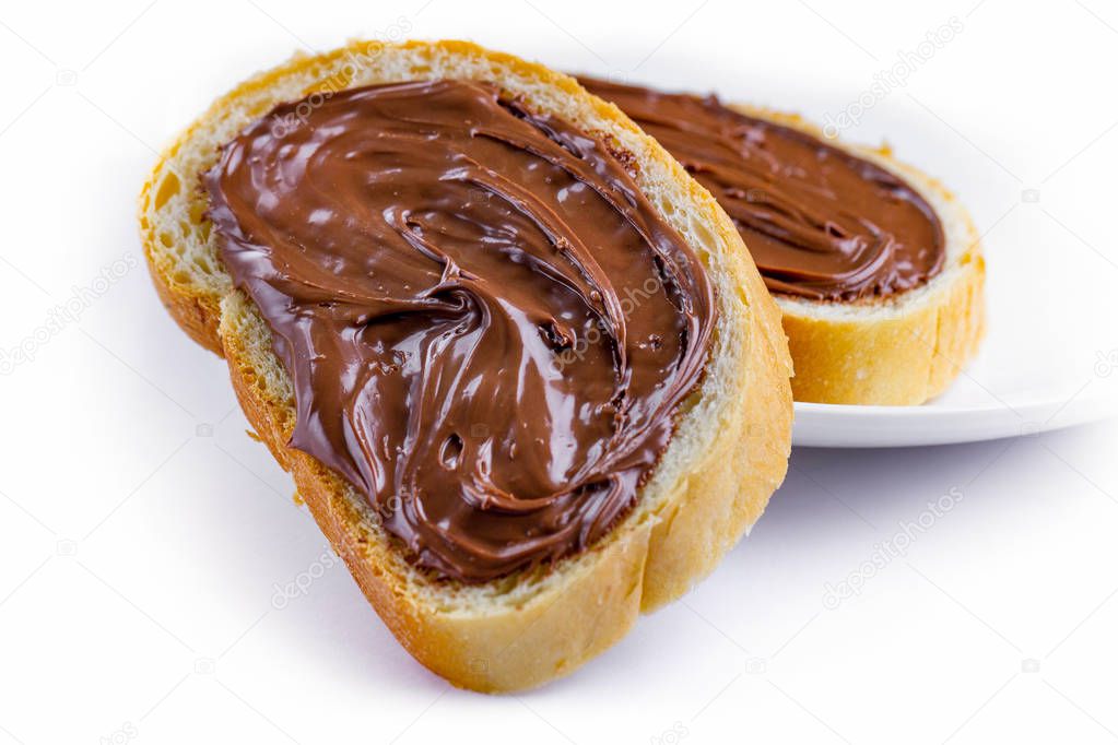 Pieces of long loaf with chocolate, nut paste on a plate. Isolated nut chocolate cream sandwiches with chocolate butter on a breakfast