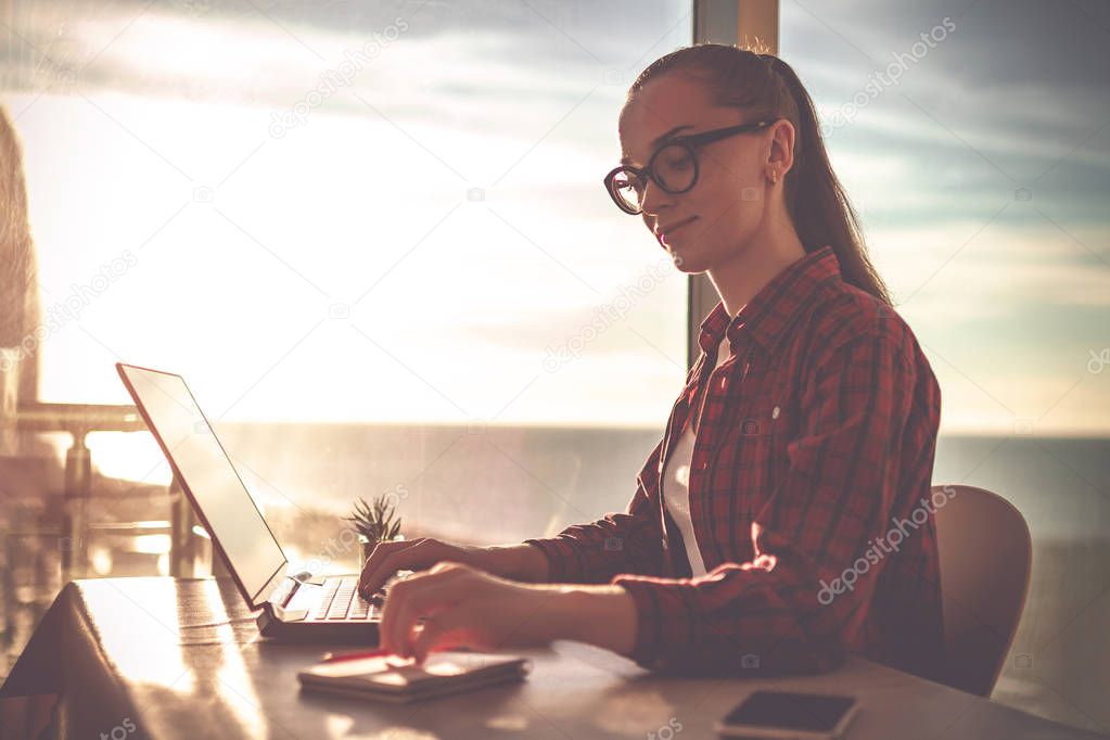 Beautiful young businesswoman in glasses working online at home with a laptop. 