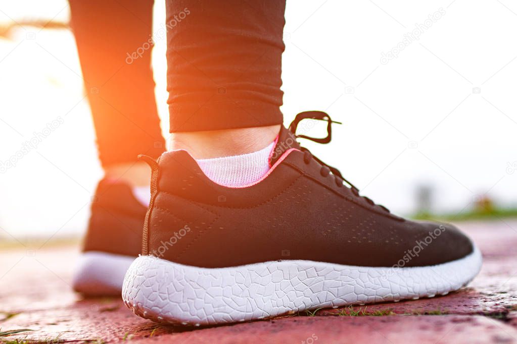 Young, fitness woman in sneakers engaged in sports training and jogging at sunset. Sports lifestyle