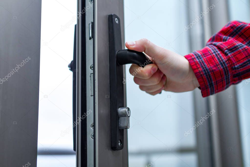 A man opens the glass balcony door. Hand holds door knob on glass door