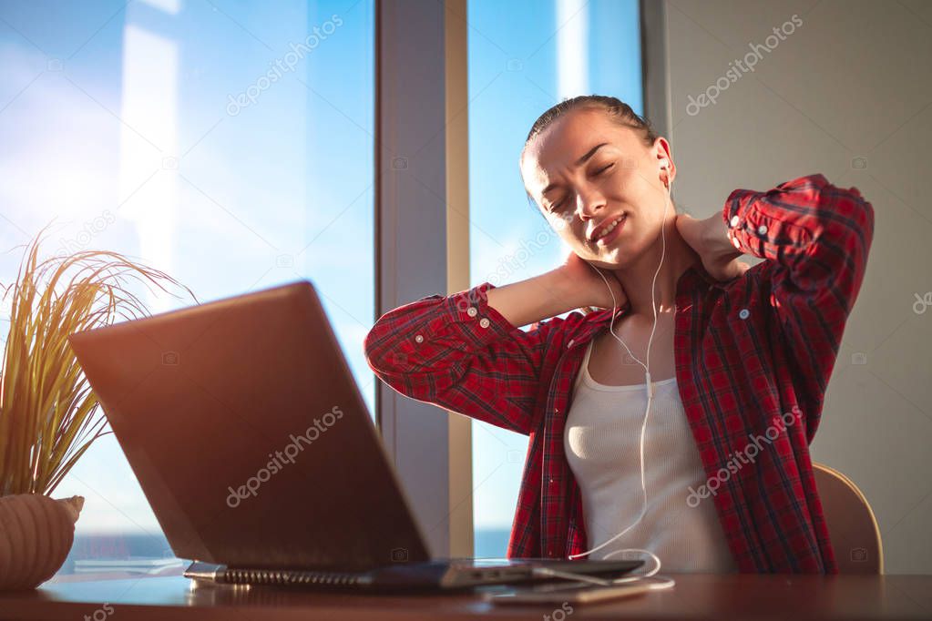 Young woman feels discomfort in the cervical spine and massaging stiff neck to relieve pain in muscles after long hours of work at the computer. Suffering from fibromyalgia at work. 