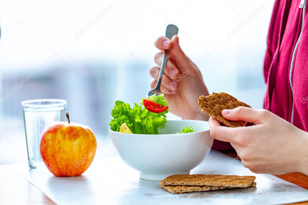 Young woman is eating a healthy, fresh, vegetable salad with crisp rye bread. Diet and healthy lifestyle concept. Diet food. Proper nutrition and eat right 
