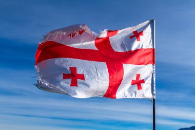 Gürcü bayrağı mavi, açık gökyüzü arka planda rüzgarda sallayarak