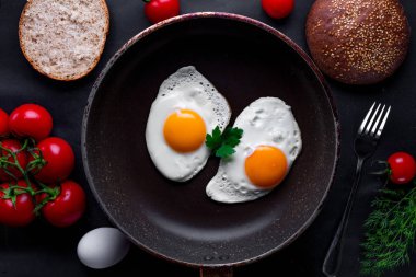 Bir kızartma içinde ev yapımı, taze, kızarmış yumurta için sağlıklı bir kahvaltı ile dereotu, maydanoz, domates ve susam çörek tava. Üstten Görünüm. Protein yiyecek