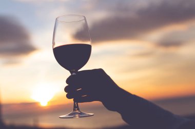 Bir bardak şarap akşam günbatımında el. 