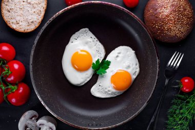 Ev yapımı, kızarmış tavuk yumurtası, dereotu, maydanoz, domates kiraz ve susam topuz ile sağlıklı bir kahvaltı için bir tava. Üst görünüm. Protein gıda