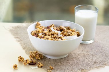 Kahvaltılık kuru. Keten tohumu, kızılcık ve Hindistan cevizi ve bir bardak süt bir tabloda bir granola kase gevrek tatlım. Sağlıklı ve lif yiyecek. Kahvaltı saati 