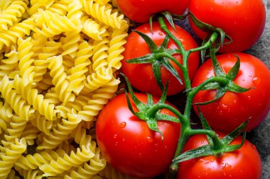 Pişmiş, kurutulmuş düdük ve taze domates yakın. İtalyan yemeği. Makarna pişirme için malzemeler