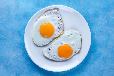 Kızarmış tavuk bir plaka üzerinde mavi bir arka plan üzerinde sağlıklı bir kahvaltı için yumurta. Protein yiyecek. Üstten Görünüm