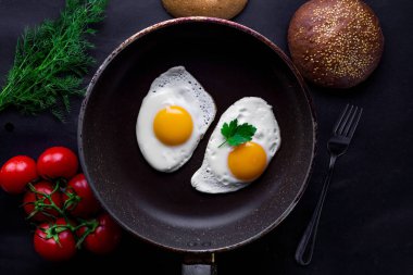 Bir kızartma içinde ev yapımı, taze, kızarmış yumurta için sağlıklı bir kahvaltı ile dereotu, maydanoz, domates ve susam çörek tava. Üstten Görünüm. Protein yiyecek