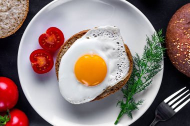 Ev yapımı, kızarmış tavuk yumurtası, dereotu ile bir tabak, domates kiraz ve susam topuz sağlıklı bir kahvaltı için. Protein yemeği. Yumurta sandviçleri. Üst görünüm  