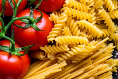 Pişmiş, Kurutulmuş spagetti, düdük ve taze domates dokusu. İtalyan gıda konsepti. Makarna pişirme için malzemeler. 