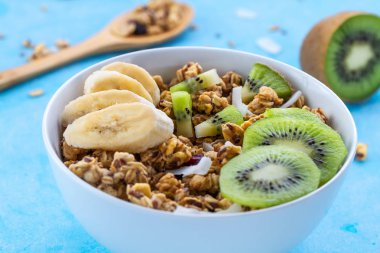 Kahvaltılık kuru. Dilim taze muz ve kivi mavi bir arka plan üzerinde ile müsli kase gevrek tatlım. Sağlıklı, fitness ve fiber yiyecek. Kahvaltı saati 