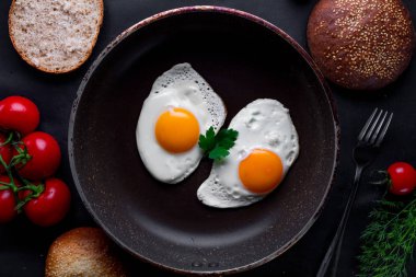 Bir kızartma içinde ev yapımı, taze, kızarmış yumurta için sağlıklı bir kahvaltı ile dereotu, maydanoz, domates ve susam çörek tava. Üstten Görünüm. Protein yiyecek