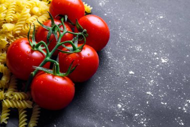 Siyah bir arka planda kurutulmuş düdük ve taze domates. İtalyan yemeği. Boşluk Kopyala. Makarna pişirme için malzemeler