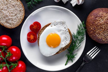 Ev yapımı, kızarmış tavuk yumurtası, dereotu ile bir tabak, domates kiraz ve susam topuz sağlıklı bir kahvaltı için. Protein yemeği. Yumurta sandviçleri. Üst görünüm  