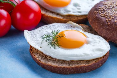 Mavi arka planda sağlıklı bir kahvaltı için ev yapımı, kızarmış tavuk yumurtası ile çörekler. Protein yemeği. Yumurta sandviçler 