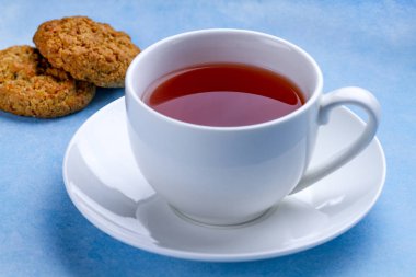 Yulaf ezmeli kurabiye ve mavi bir arka plan üzerine bir fincan çay. Un, tahıl tatlı ve sıcak içecek 