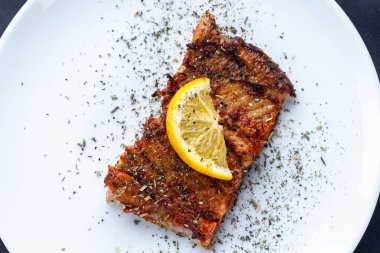Sulu limon, baharatlar ve otlar beyaz bir plaka üzerinde bir dilim taze, ızgara somon fileto 