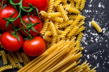 Pişmiş spagetti, düdük ve taze domates dokusu. Yemek konsepti. İtalyan makarna pişirme için malzemeler. 