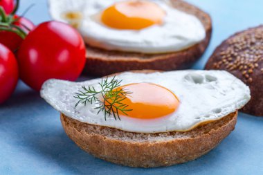 Mavi arka planda sağlıklı bir kahvaltı için ev yapımı, kızarmış tavuk yumurtası ile çörekler. Protein yemeği. Yumurta sandviçler 