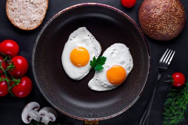 Dereotu, maydanoz, domates kiraz ve susam çörek için sağlıklı bir kahvaltı ile bir tavada kızarmış yumurta. Üstten Görünüm. Protein yiyecek