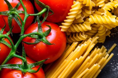 Pişmiş, Kurutulmuş spagetti, düdük ve taze domates dokusu. İtalyan gıda konsepti. Makarna pişirme için malzemeler. 