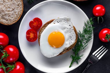 Ev yapımı, kızarmış tavuk yumurtası, dereotu ile bir tabak, domates kiraz ve susam topuz sağlıklı bir kahvaltı için. Protein yemeği. Yumurta sandviçleri. Üst görünüm  