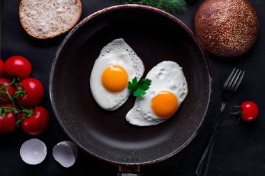 Dereotu, maydanoz, domates kiraz ve susam çörek için sağlıklı bir kahvaltı ile bir tavada kızarmış yumurta. Üstten Görünüm. Protein yiyecek