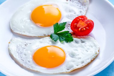 Ev yapımı, taze maydanoz ve kiraz domates ile kızarmış tavuk yumurtası sağlıklı bir kahvaltı için bir plaka üzerinde yakın. Protein gıda. 