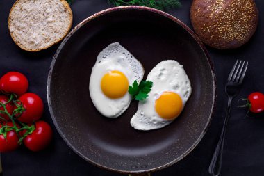 Dereotu, maydanoz, domates kiraz ve susam çörek için sağlıklı bir kahvaltı ile bir tavada kızarmış yumurta. Üstten Görünüm. Protein yiyecek