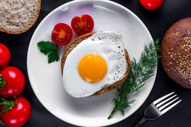 Ev yapımı, kızarmış tavuk yumurtası ile bir plaka üzerinde dereotu, maydanoz, domates kiraz ve susam topuz sağlıklı bir kahvaltı için. Protein yemeği. Yumurta sandviçleri. Üst görünüm  