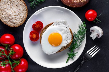 Dereotu ile bir plaka üzerinde kızarmış tavuk yumurtası, sağlıklı bir kahvaltı için domates kiraz ve susam topuz. Protein yemeği. Yumurta sandviçleri. Üst görünüm  