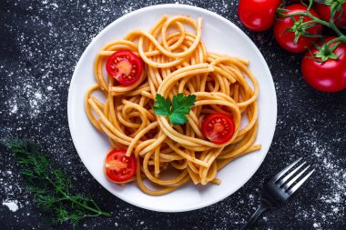 Maydanoz, dereotu, kiraz domates ve domates soslu bir plaka üzerinde leziz spagetti. İtalyan gıda ve makarna. Üstten Görünüm 