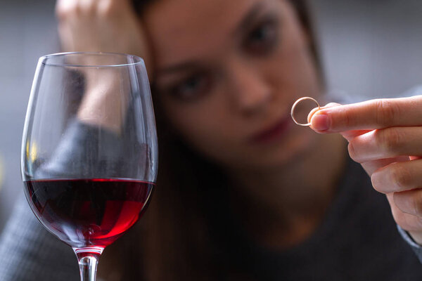 Плачущая, разведенная женщина держит и смотрит на обручальное кольцо и
