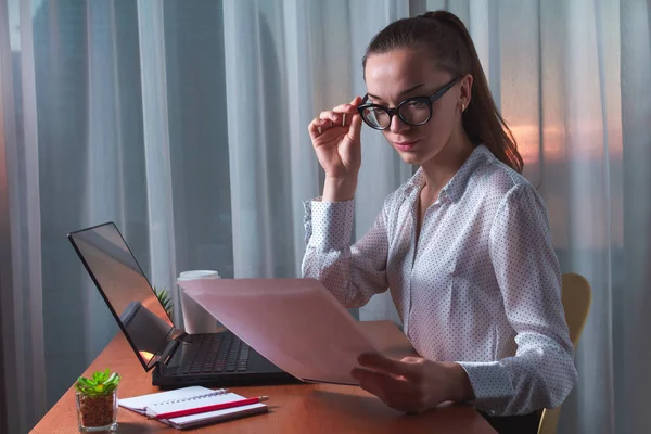 Busy, young business woman in spectacles is reading and checking