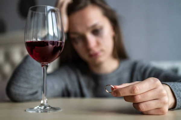 Weinend hält die geschiedene Frau einen Ehering in der Hand und dri — Stockfoto