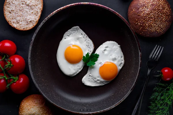 Bir kızartma içinde ev yapımı, taze, kızarmış yumurta için sağlıklı bir kahvaltı ile dereotu, maydanoz, domates ve susam çörek tava. Üstten Görünüm. Protein yiyecek